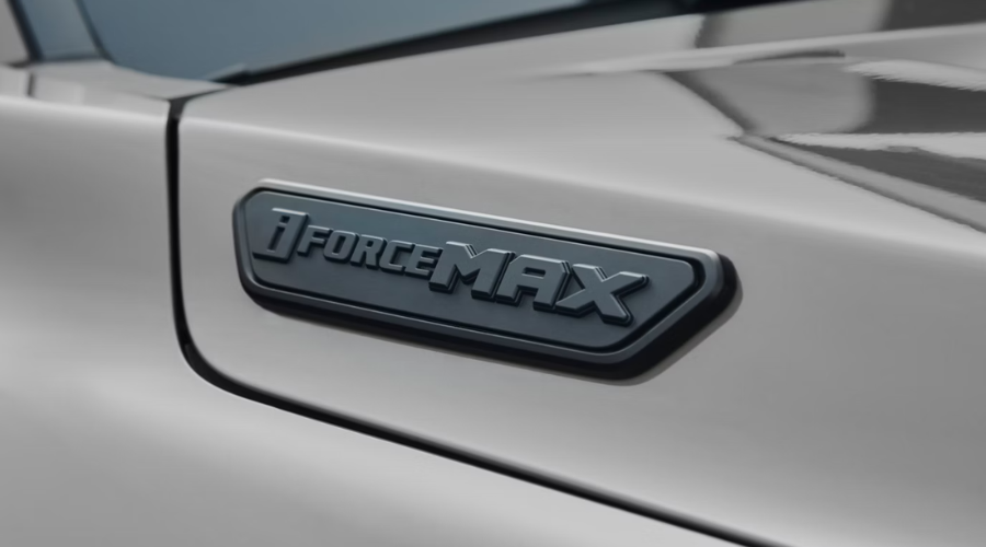 Close-up of the matte black i-FORCE MAX hybrid badge on a silver 2026 Toyota truck hood, highlighting high-torque powertrain options available on both 2026 Tacoma and Tundra models for Lake County drivers near Waukegan and Libertyville, IL.