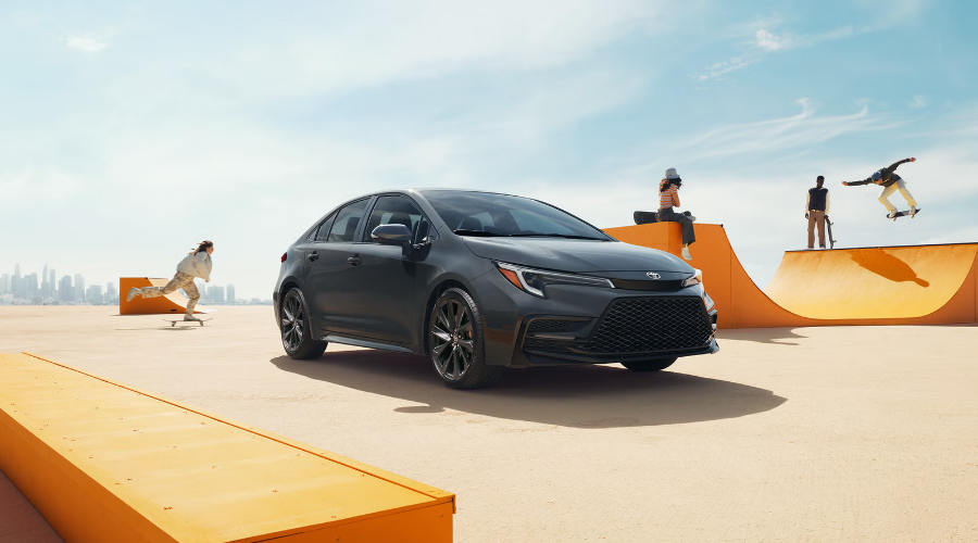 New 2027 Toyota Corolla SE sedan in dark Inked paint exterior with dark alloy wheels parked at an outdoor skatepark near Waukegan, IL, available now at Classic Toyota.